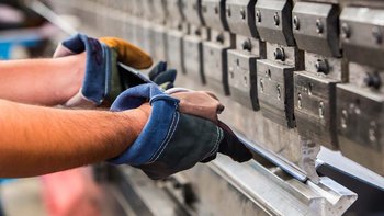 Eine Kantmaschine in dem zwei Männerhände ein Blech halten